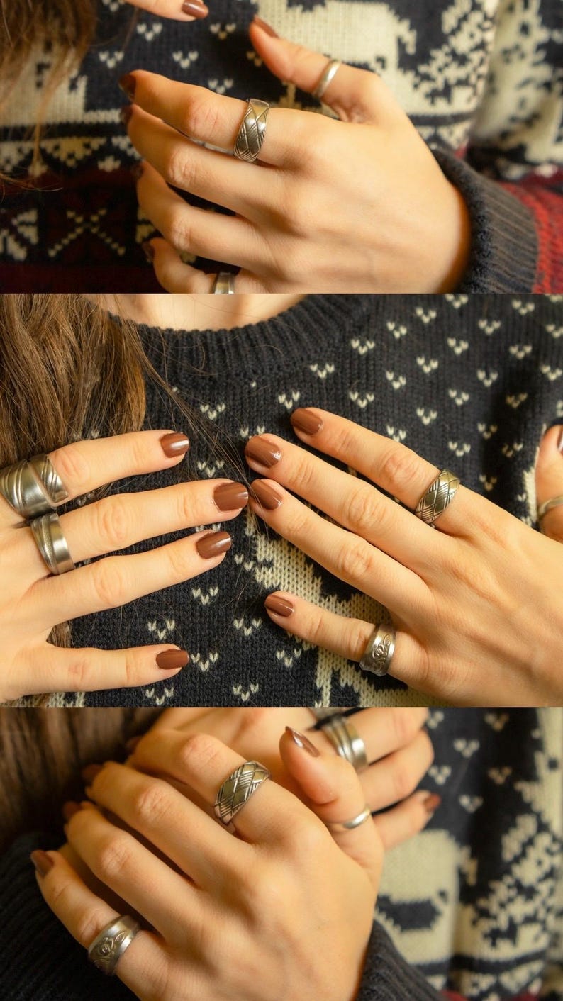 May include: Close-up of hands wearing multiple silver rings with a woven design. The nails are painted a rich brown color.
