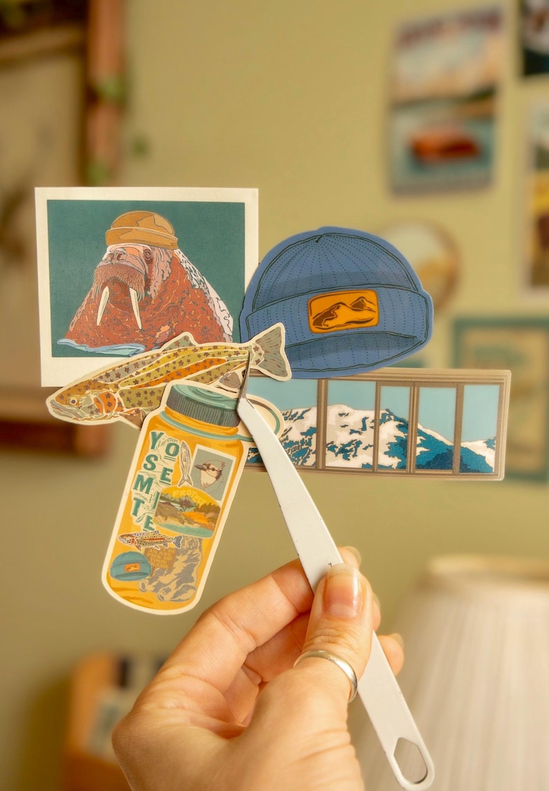 May include: A set of five stickers featuring a walrus wearing a hat, a trout, a mountain range, a window view, and a water bottle with the word "Yosemite" on it.