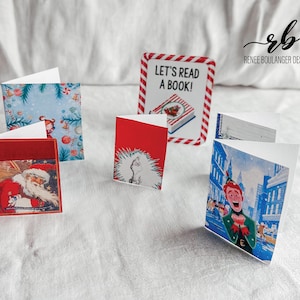 May include: A collection of small, folded greeting cards with various holiday-themed illustrations. Designs include Santa Claus, a Dr. Seuss character, and a winter scene. One card reads "Let's Read a Book!" in a red and white striped border.
