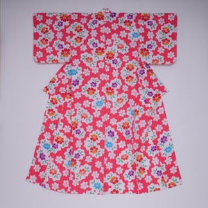 May include: A pink and white yukata with a floral pattern. The yukata has a traditional Japanese design with a wide collar and sleeves.