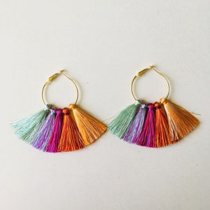 May include: A pair of gold hoop earrings with colorful tassel fringe. The tassels are in shades of orange, pink, purple, and green.