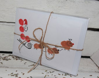 May include: A set of blank Christmas cards with a hand-painted design of Santa Claus in a sleigh pulled by reindeer. The cards are tied together with twine.