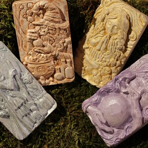 K&ouml;nnte beinhalten: Vier dekorative Seifenst&uuml;cke mit Fantasy-Motiv. Jedes St&uuml;ck zeigt einen anderen Charakter, darunter eine Hexe, ein Gnom, ein Zauberer und eine Fee. Die Seifen sind in verschiedenen Farben gehalten, darunter Lila, Blau, Braun und Wei&szlig;.