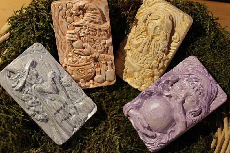 K&ouml;nnte beinhalten: Vier dekorative Seifenst&uuml;cke mit Fantasy-Motiv. Jedes St&uuml;ck zeigt einen anderen Charakter, darunter eine Hexe, ein Gnom, ein Zauberer und eine Fee. Die Seifen sind in verschiedenen Farben gehalten, darunter Lila, Blau, Braun und Wei&szlig;.