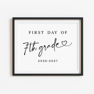 May include: A black framed sign featuring white background with black text that reads FIRST DAY OF 7th grade with a small heart icon at the end of the word grade and the school year 2026-2027 printed in a simple serif font at the bottom.