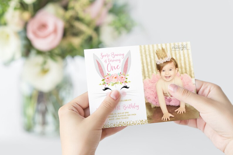 May include: A pink and white bunny rabbit with a floral crown and eyelashes. The text "Some Bunny is turning One" is on the invitation. The invitation has a gold glitter background. A photo of a baby girl wearing a pink tutu and a gold crown is on the right side of the invitation.