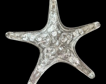 May include: A clear glass starfish ornament with a textured surface. The starfish is a popular nautical decor item.