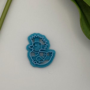 May include: A light blue duck-shaped cookie cutter with a spiky mohawk and two round details on its side. The cutter is made of plastic and has a detailed outline. The duck is sitting in a body of water.