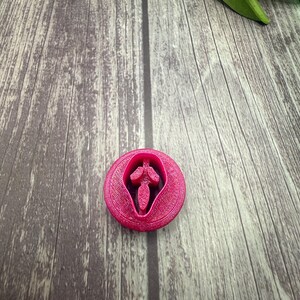 May include: A pink plastic cookie cutter shaped like the Ghostface mask from the Scream movie franchise.