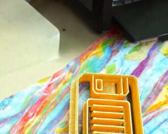 May include: A gold-colored 3D printed floppy disk icon. The icon is on a colorful surface.