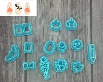 May include: A collection of blue plastic Halloween-themed cookie cutters in various shapes, including pumpkins, ghosts, bats, and a skeleton. The image also shows examples of cookies made with the cutters.