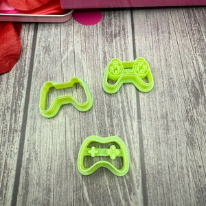 May include: Three lime green plastic cookie cutters shaped like video game controllers.