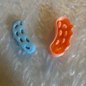 May include: Two small, colorful, textured, plastic objects. One is light blue and the other is peach.