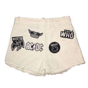 May include: White denim shorts with various band patches including Led Zeppelin, AC/DC, Nirvana, and The Who.
