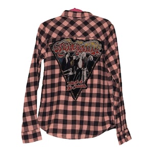 May include: A pink and black plaid flannel shirt with a large, colorful patch on the back. The patch features a band called "Styx" and the text "Rock a  Mr. Suicide".