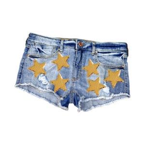 May include: Blue denim shorts with frayed edges and five gold star patches.