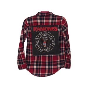 May include: Red and black plaid flannel shirt with a black patch on the back that says "RAMONES" in red letters with a circle around it that says "JOHNNY, TOMMY, DEDEE, JOEY" in white letters.