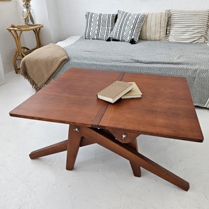 May include: A white ceramic mug with a black handle and the text "But First, Coffee" in a bold, black font. The mug is set against a neutral background, highlighting its simple design.