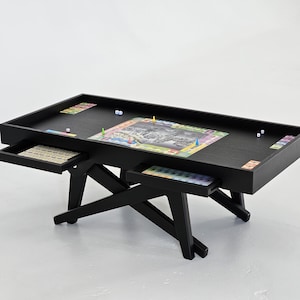 May include: A black wooden game table with a colourful game board and dice. The table has two pull-out drawers for storing game pieces.