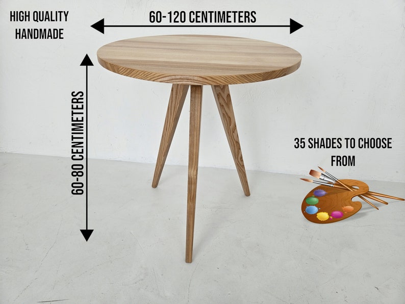 May include: A round wooden table with three legs. The table is 60-120 centimeters wide and 60-80 centimeters tall. The table is made of natural wood and has a light brown color. The text "HIGH QUALITY HANDMADE" is visible in the top left corner of the image. The text "60-120 CENTIMETERS" is visible above the table. The text "60-80 CENTIMETERS" is visible to the left of the table. The text "35 SHADES TO CHOOSE FROM" is visible in the bottom right corner of the image.