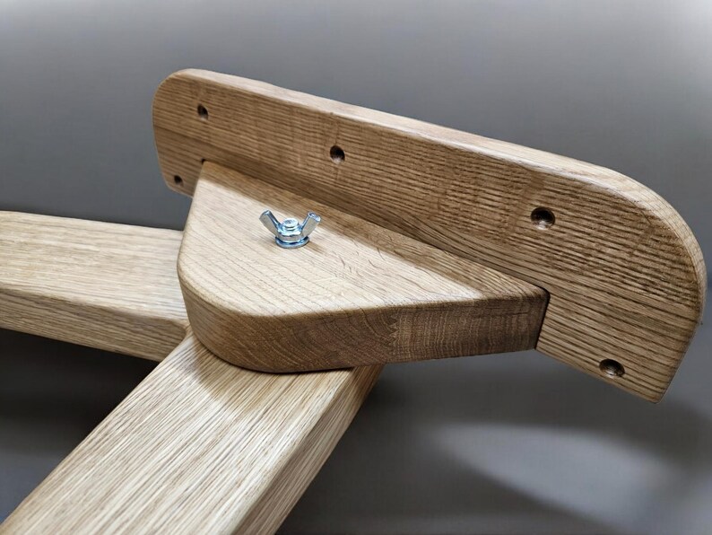 May include: Close-up of a wooden furniture piece with a triangular support and a metal nut. The wood is light brown and has a natural grain pattern.