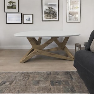 May include: White oval coffee table with a unique, geometric wooden base. The table has a modern design and is perfect for a living room or den.