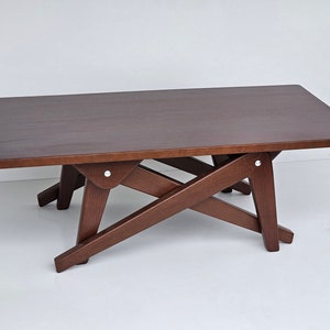 May include: A dark brown wooden coffee table with a rectangular top and a unique X-shaped base. The table has a simple, modern design.