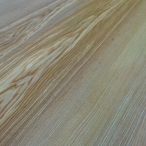 May include: Close-up of a light brown wood surface with a natural grain pattern.
