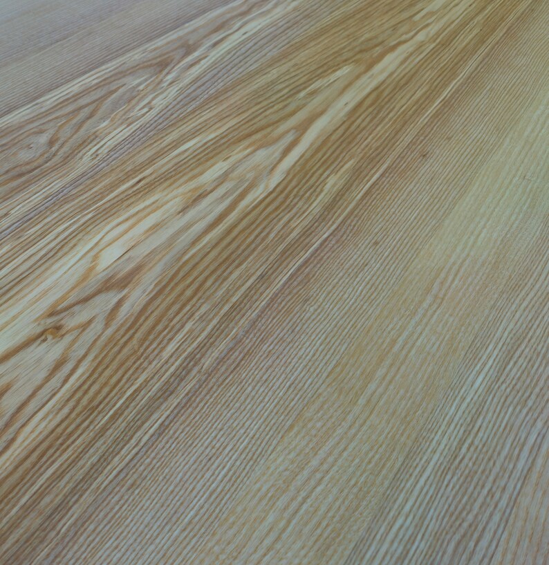 May include: Close-up of a light brown wood surface with a natural grain pattern.
