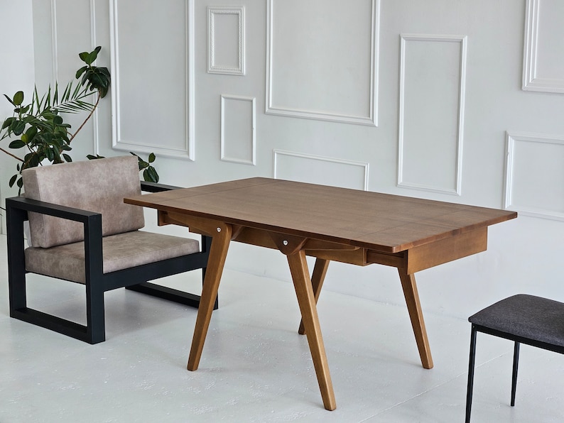 Puede incluir: Una mesa de madera marr&oacute;n con un caj&oacute;n y una silla de metal negro. La mesa tiene una tapa rectangular y cuatro patas. La silla tiene un asiento acolchado y un marco de metal negro.