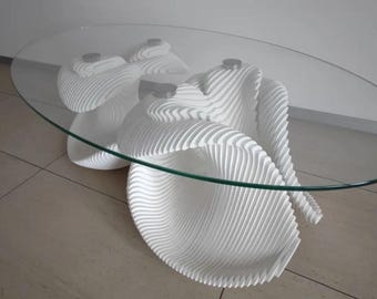 May include: White coffee table with a glass top and a unique, organic, wave-like design. The table is made of layered wood and has a modern, minimalist aesthetic.