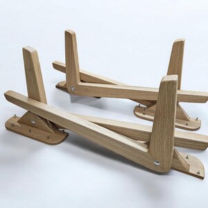 May include: Two wooden laptop stands, each with a triangular base and a folding design. The stands are made of light brown wood and have a natural finish.