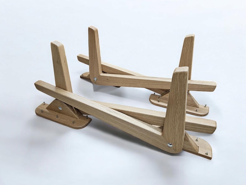 May include: Two wooden laptop stands, each with a triangular base and a folding design. The stands are made of light brown wood and have a natural finish.