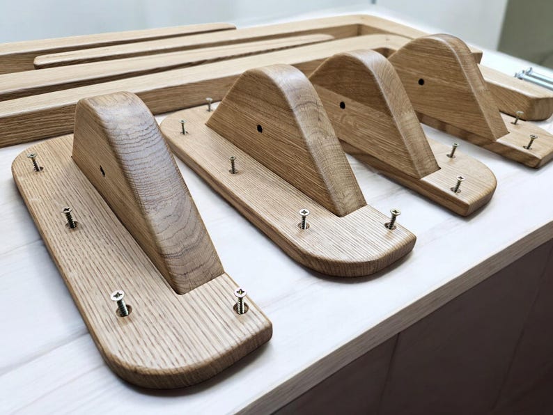 May include: Four wooden shelf brackets with a curved top and a flat bottom. Each bracket has several screws securing it to a wooden surface.