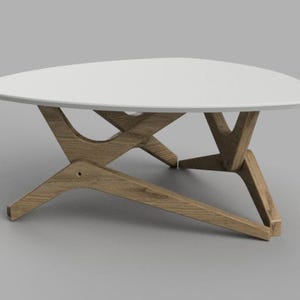 May include: A white triangular coffee table with a unique wooden base. The base is made of four pieces of wood that are connected in a criss-cross pattern.