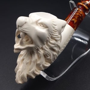 May include: A white meerschaum pipe with a wolf head design. The pipe has a brown and orange stem.