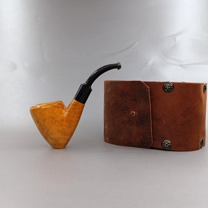 May include: A light brown wooden pipe with a black mouthpiece and a brown leather carrying case with metal accents.