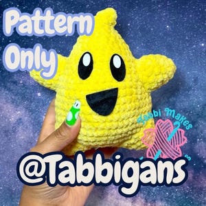 Könnte beinhalten: Ein gelbes sternförmiges Kuscheltier mit schwarzen Augen und einem lächelnden Mund. Der Text "Pattern Only" steht über dem Stern. Der Text "@Tabbigans" steht unten. Das Spielzeug wird von einer Hand mit einem grün-weißen Nagel gehalten.