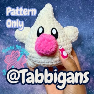 Puede incluir: Un juguete de peluche en forma de estrella, tejido a ganchillo, con una nariz rosa y ojos negros. El texto "Pattern Only" es visible, junto con el nombre del creador, "@Tabbigans". El juguete es de color crema y tiene una apariencia texturizada.