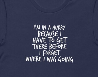 May include: Navy blue t-shirt with white text that reads "I'm in a hurry because I have to get there before I forget where I was going."