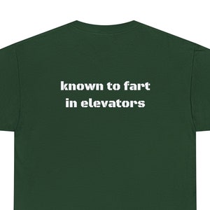 May include: A dark green t-shirt with the text "known to fart in elevators" printed in white on the back.