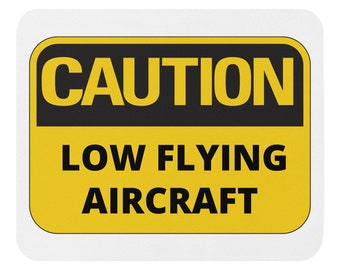 Puede incluir: Una señal de precaución amarilla y negra con el texto "PRECAUCIÓN AVIONES DE BAJA ALTURA".