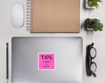 May include: Pink square sticker with black text that reads "TIPS THANKS A LATTE" on a silver laptop.