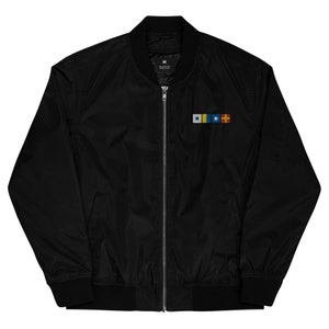 May include: A black bomber jacket with a zipper closure and a small embroidered design on the left chest. The design features four colorful squares.