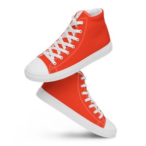 Op de afbeelding: Een paar hoge sneakers in een levendige rode kleur. De schoenen hebben witte veters, een witte neus en een witte zool. De sneakers zijn ontworpen in een klassieke, casual stijl.