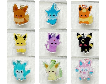 May include: Nine colourful Pokemon character charms, each with a different design. The charms are made of clear acrylic and feature a variety of Pokemon characters, including Eevee, Vaporeon, Jolteon, Flareon, Espeon, Umbreon, Leafeon, Glaceon, and Sylveon.