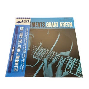 May include: A vinyl record album titled "Idle Moments" by Grant Green. The album cover features a close-up of a guitar and the text "Celebrating the Finest Jazz Since 1939". The album is a limited edition 180-gram blue color vinyl.