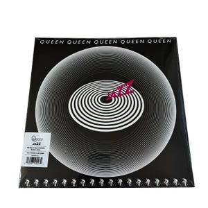 May include: A sealed vinyl record album titled "Jazz" by Queen. The album cover is black with a white concentric spiral design and the word "Jazz" in a stylized red font. The top of the cover reads "Queen" repeatedly.