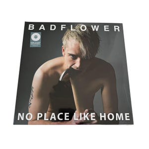 May include: A vinyl record album titled "BADFLOWER" with the text "NO PLACE LIKE HOME." The album cover features a person with blonde hair, and a tattoo on their arm. The album has a "PURE CLOUDY COLOR VINYL" sticker.