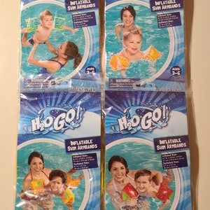 May include: Four packages of H2O GO! inflatable swim armbands. Each package features a child and adult in a pool, with the child wearing the armbands. The packages are blue and yellow, with the text "INFLATABLE SWIM ARMBANDS" and "AGES 3-6". The inflated size is 6.7 in x 4.9 in x 5.9 in.